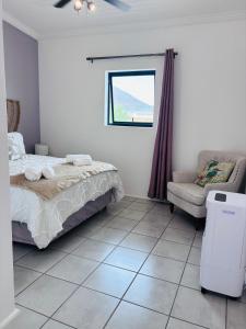 a bedroom with a bed and a chair and a window at Capri Horizon Hideaway in Fish Hoek