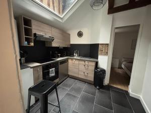 a small kitchen with a sink and a stool in it at charmant appartement 4 pers hyper centre, au calme in Rouen