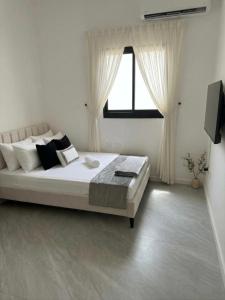 a white bedroom with a large bed with a window at פנטהאוז Siesta in Eilat