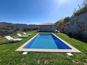 a pool in a yard with two chairs and a building at Casa Sambinho II Bela Vista in Rio Caldo
