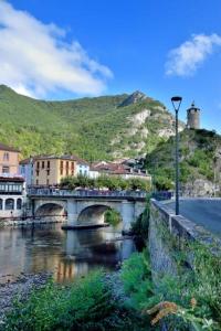 a bridge over a river with buildings and a mountain at Les Gîtes d'Altaïr - La Petite Ourse in Tarascon-sur-Ariège