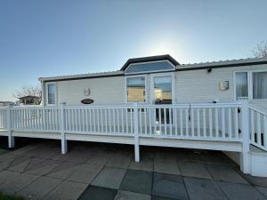 a mobile home with a white railing and a porch at Summer Meadows at Sandy Bay in North Seaton