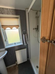 a bathroom with a shower and a sink and a window at Summer Meadows at Sandy Bay in North Seaton +6 photos