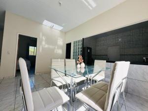 a dining room with a glass table and white chairs at Casa da Lua in Barreirinhas