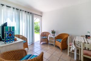 a living room with wicker chairs and a table and a television at Ria's Rest Self Catering Flatlet in Sedgefield