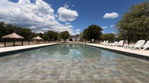 a swimming pool with white chairs at Complejo Sol y Sombra in San Javier