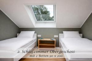 two beds in a small room with a window at Ferienwohnung Feinheit - Gulfhof nahe Greetsiel mit Sauna, Garten & 3 Schlafzimmern in Krummhörn