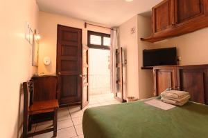 a bedroom with a green bed and a television at HOTEL NIUT-JA in Oaxaca City