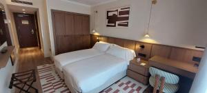 a small bedroom with a white bed and a desk at Palacio Valderrabanos in Ávila