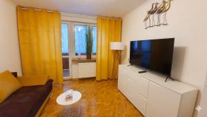 a living room with a flat screen tv on a dresser at Apartament Motylek in Hajnówka +3 photos