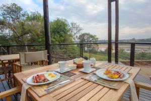 a wooden table with plates of food on a balcony at Kruger Private Lodge in Marloth Park +21 photos