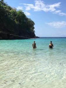 two men standing in the water at the beach at Riddim Vybz guesthouse in Kingston
