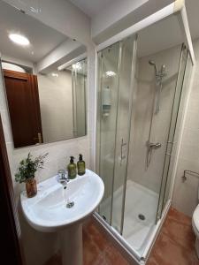 a bathroom with a white sink and a shower at La Costa Suite in Gijón