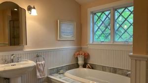 a bathroom with a sink and a tub and a window at Cutest Cottage On Central in Cape May Point +18 photos