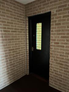 a black door with a window in a brick wall at River View Apartment in Elgin