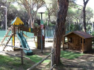 a playground with a slide and a tree at Camping Eden in Marina di Grosseto