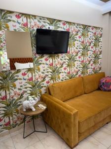 a living room with a couch and a tv at Greek House Hotel in Neos Marmaras