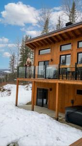 a dog sitting on the deck of a house in the snow at Chalet L'Orée Étoilée in La Tuque +15 photos