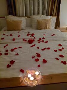 a bunch of red roses on a bed with candles at Luxury Love Cottage Spa- privatni jacuzzi &sauna , mir i privatnost in Velika Gorica