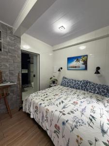 a bedroom with a bed with a floral bedspread and a desk at vista mar suite luxo in Angra dos Reis +12 photos