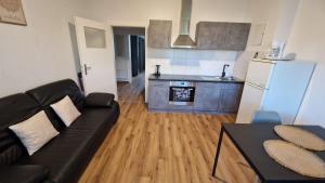 a living room with a black couch and a kitchen at Viktoria's Appartment 2 in OB-Mitte in Oberhausen