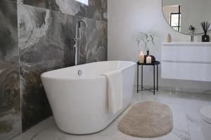 a white bathroom with a tub and a sink at Bergen Delight in Bergen