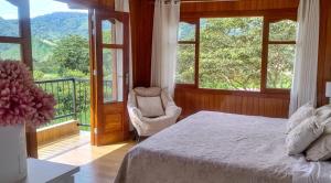 a bedroom with a bed and a balcony with windows at Villa Amaranto Oxapampa in Oxapampa