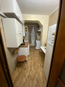 a kitchen with white cabinets and a table and a refrigerator at Lemora Apartments 3 in Focşani