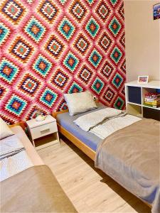 a room with two beds and a colorful wall at Lelle-kert Apartman 02 in Balatonlelle