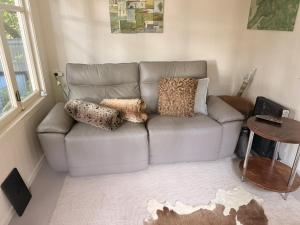 a couch in a living room with pillows on it at Little Palm Beach Hideaway in Waiheke Island