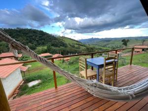 a hammock on a deck with a table and chairs at La Maison De Bonneval in São Bento do Sapucaí