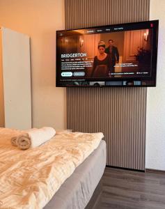 a flat screen tv hanging on a wall with a bed at daroomz in Gloggnitz +2 photos