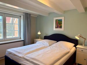 a bedroom with a large bed with white sheets and two lamps at Altes Friesenhaus West in Morsum