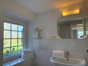 a white bathroom with a sink and a mirror at Altes Friesenhaus West in Morsum +21 photos