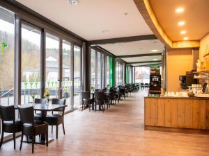 a dining room with tables and chairs and windows at Hambachtal nature hideaway boutique resort in Oberhambach