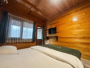 a bedroom with a bed with wooden walls and a tv at Doga Motel in Uzungöl
