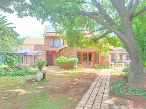 a brick house with a tree in the yard at Jolly Suites in Midrand