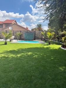 a yard with a green lawn with a swimming pool at Grey heron in Boksburg