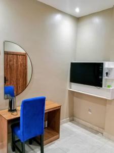 a room with a desk with a blue chair and a mirror at Servy Hotels in Port Harcourt