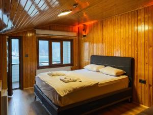 a bed in a room with wooden walls and windows at Doga Motel in Uzungöl