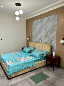 a bedroom with a bed with blue sheets and a table at Residence EBENE in Kika +16 photos