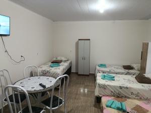 a room with three beds and a table and chairs at Pousada Paraiso in Telêmaco Borba