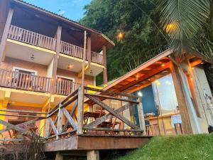 a house with a large wooden deck in front of it at Pousada Refúgio dos Palmares in São Bento do Sapucaí