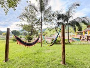 a hammock between two palm trees in a park at Pousada Refúgio dos Palmares in São Bento do Sapucaí