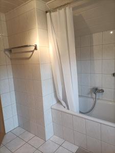 a bathroom with a tub and a shower with a shower curtain at Gästezimmer Kalletal in Kalletal
