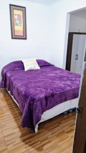 a bed with a purple comforter in a room at Casa Azul in Coñaripe +1 photo