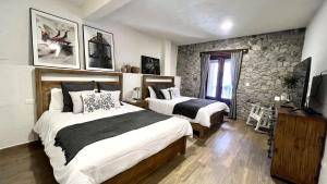a bedroom with two beds and a stone wall at Anae en ValQuirico in Santeagueda