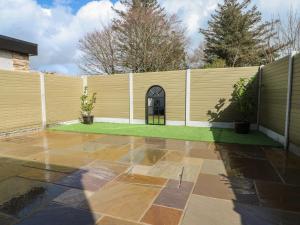 a backyard with a fence and a patio at Rhows in Llanfairpwllgwyngyll