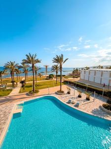 a pool with palm trees and the ocean in the background at Traumhaftes Studio mit Meerblick & Pool in Khlorakas