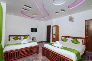 two beds in a room with green and white at Fairy Beach House - DK Resort in Pondicherry